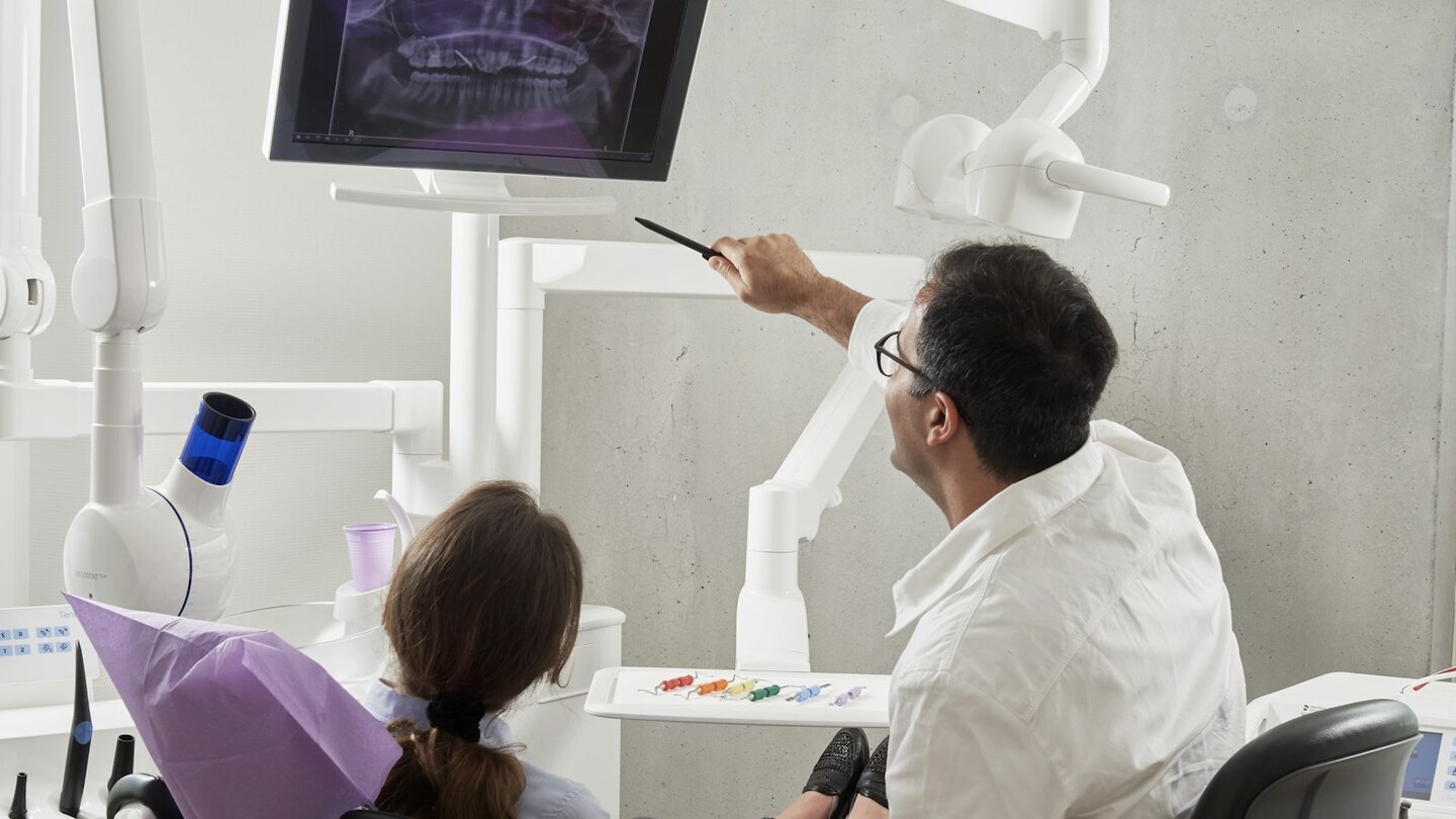 Praticien expliquant une radiographie dentaire à une patiente dans un cabinet lumineux