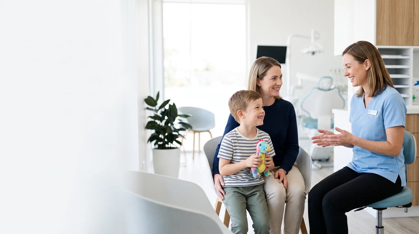 Enfant accompagné de sa mère échangeant avec une professionnelle de santé dans un cabinet dentaire lumineux