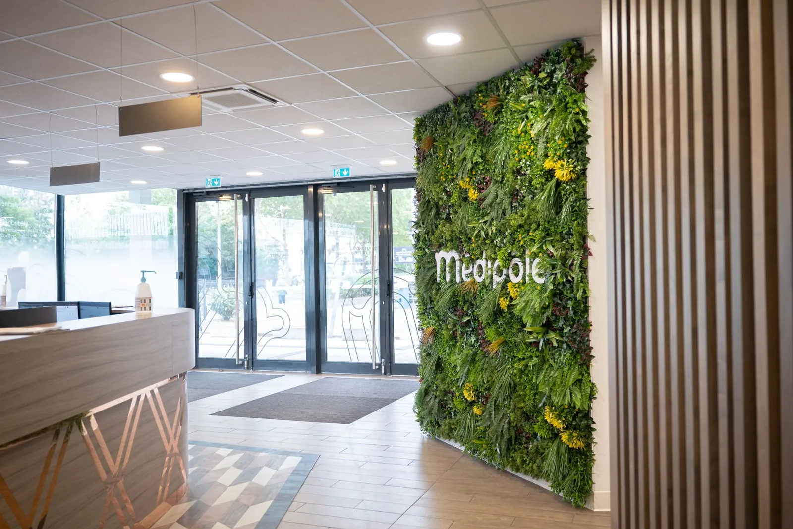 Hall d'accueil du Médipôle de Schiltigheim avec banque d'accueil et mur végétal